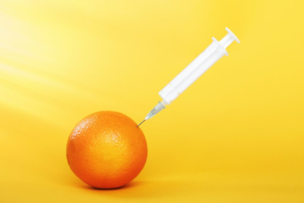 orange fruit with syringe extracting liquid with vitamin C. natural anti aging cosmetics concept
